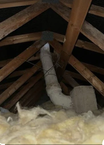Asbestos cement flue pipe running through a loft space before removal